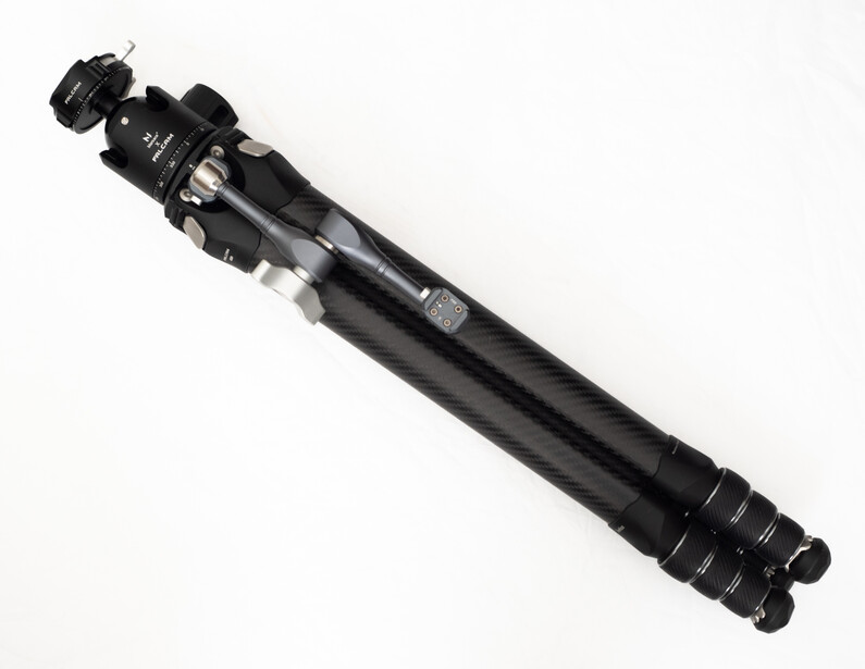 Black carbon fiber tripod with extending legs and ball head mount against white background.