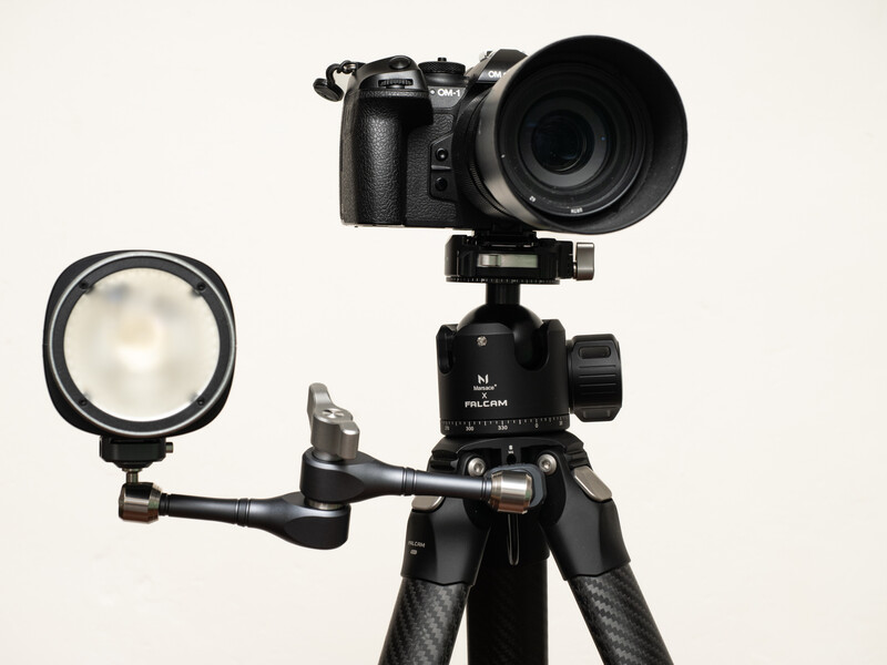 Professional camera mounted on tripod with ball head, accompanied by a ring light on articulating arm.