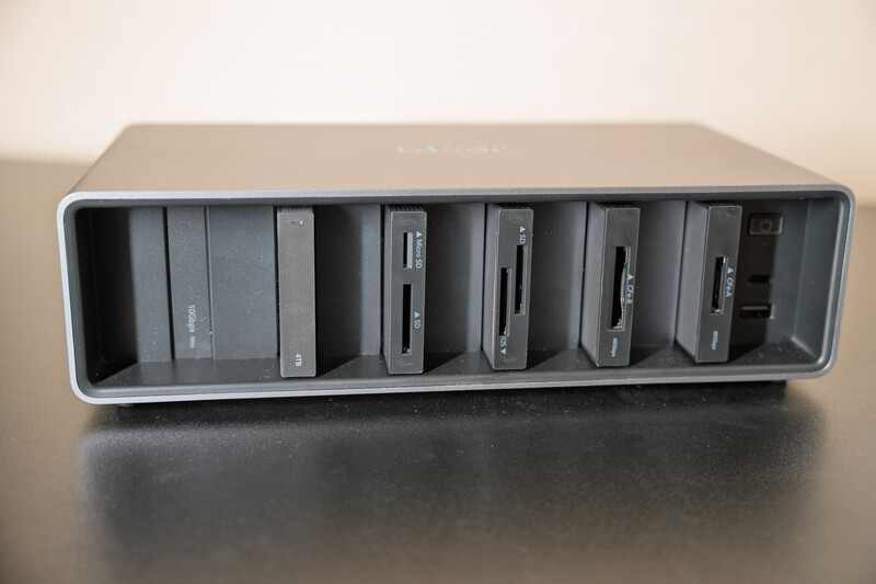 External hard drive dock with six bay slots arranged horizontally in gray plastic housing.