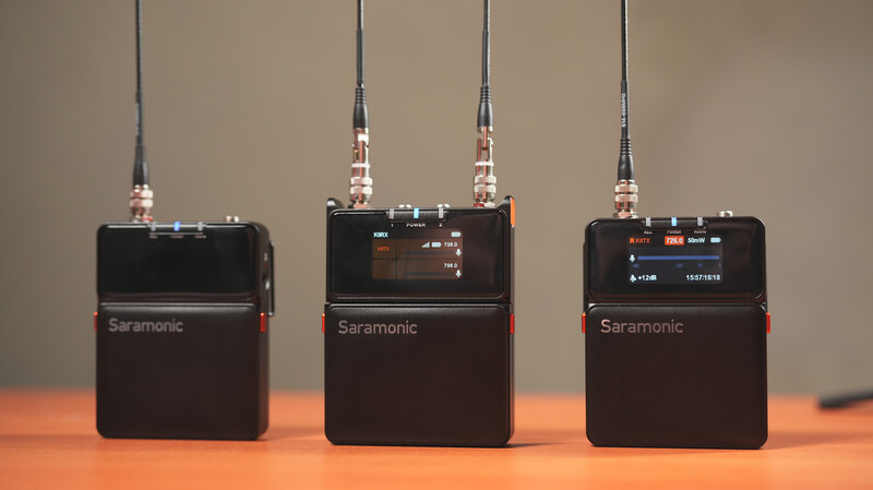 Three Saramonic wireless microphone transmitter units with antennas lined up on an orange surface.