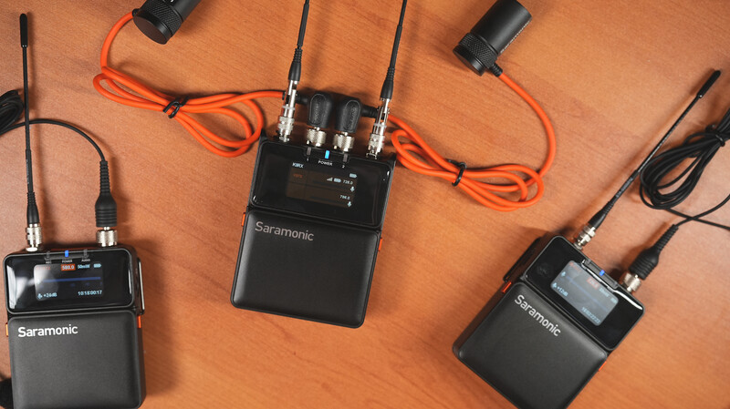 Three Saramonic wireless audio transmitter and receiver units arranged on a wooden surface with cables and antennas.