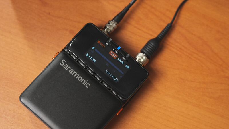 Saramonic wireless audio receiver with dual XLR connectors and LCD screen on wooden surface.