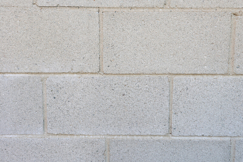 Close-up of concrete cinder blocks stacked in horizontal rows with visible mortar joints and surface texture variations.