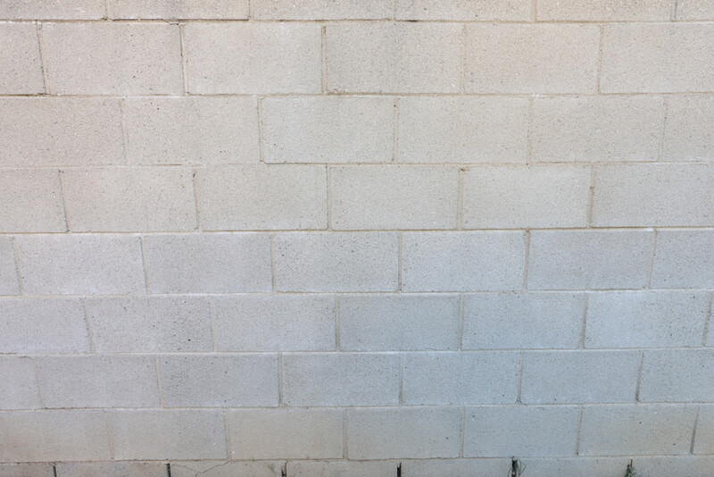 Cinder block wall with graduated lighting from warm tones at top to cool tones at bottom.