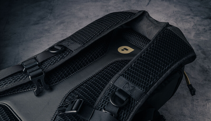 Black camera shoulder strap with textured fabric and metal hardware on concrete surface.