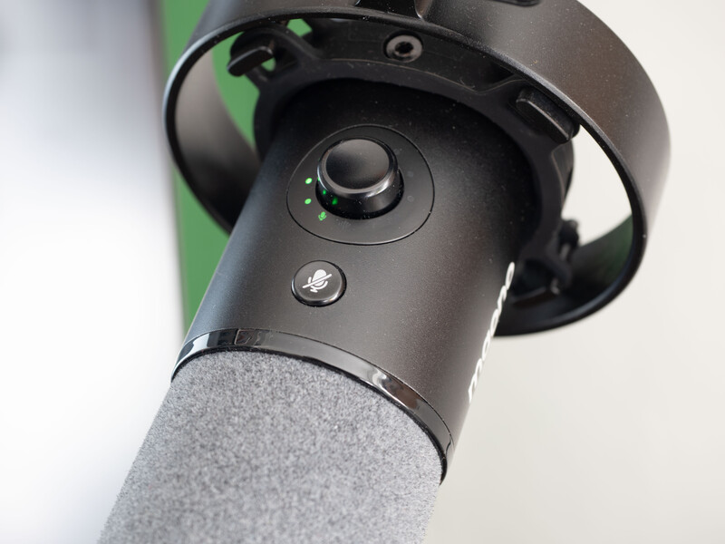 Close-up of a black gimbal head mounted on a gray tripod leg against a blurred background.