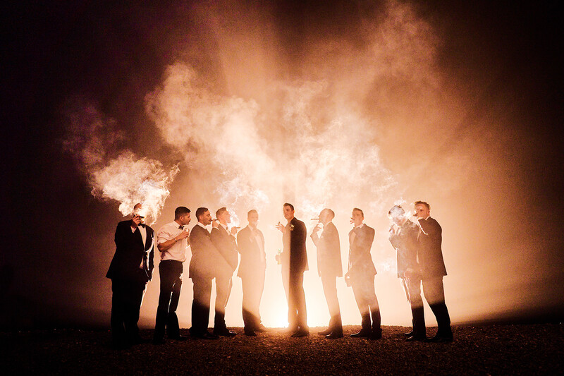 Group of men in suits silhouetted against bright, dramatic explosion and smoke.
