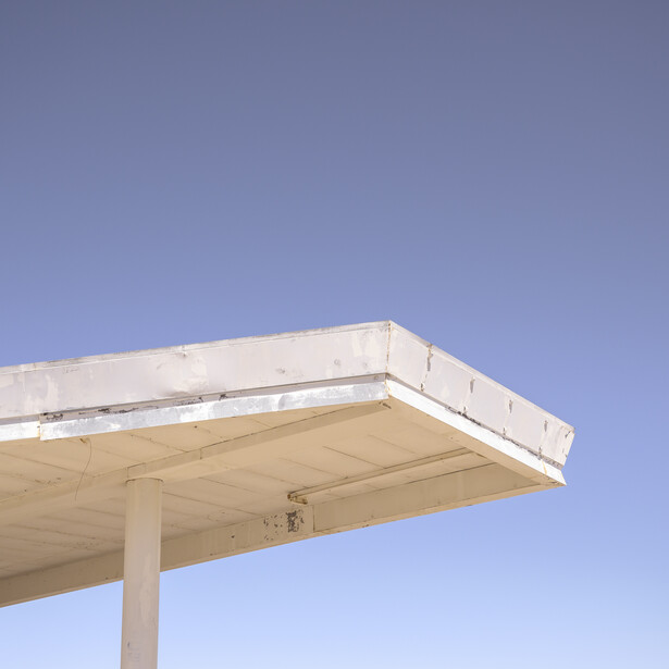 Minimalist photograph of a concrete canopy structure against a clear blue sky.