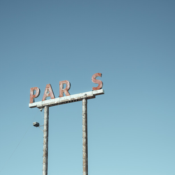 Weathered vintage neon sign reading "BAR" against a clear blue sky.