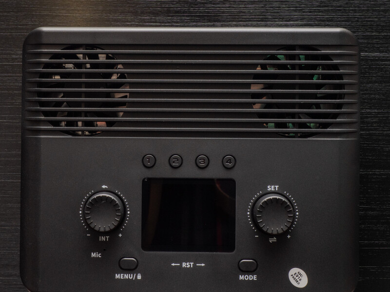Top-down view of a portable audio interface with horizontal ventilation grille, control knobs, and LCD screen.