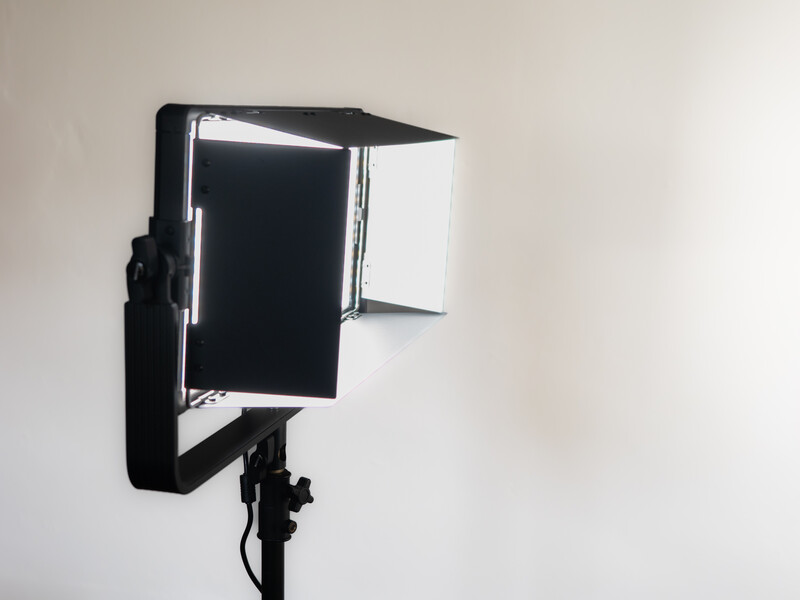 Professional LED panel light mounted on stand with diffusion panels and reflectors attached.