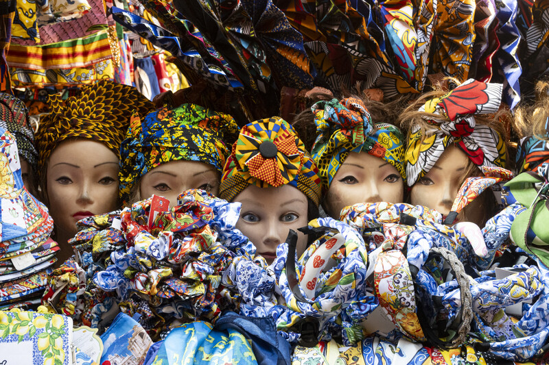 Display of colorful fabric head wraps and mannequin heads wearing patterned textiles in vibrant African prints.