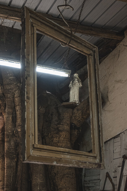 Large ornate mirror with wooden frame hanging in industrial warehouse space with exposed brick and metal ceiling.