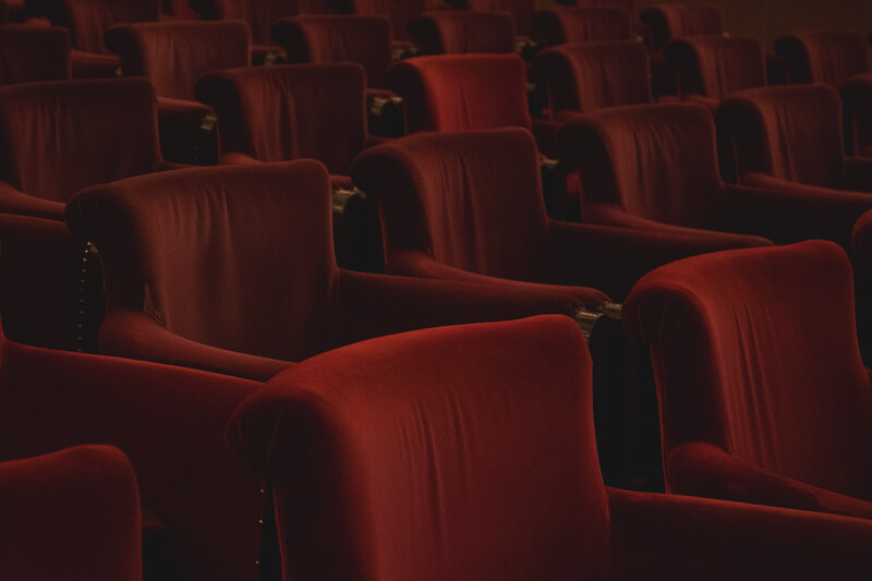 Empty movie theater with rows of red velvet seats receding into darkness.