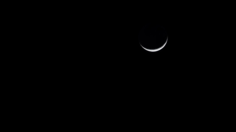A slice of moon sitting the the darkness of space. 