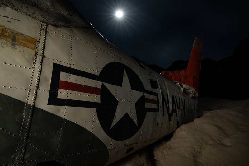 Military aircraft fuselage with U.S. star insignia illuminated at night.