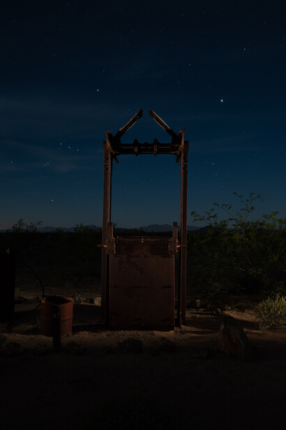 Abandoned wooden structure with open doorway silhouetted against starry night sky.