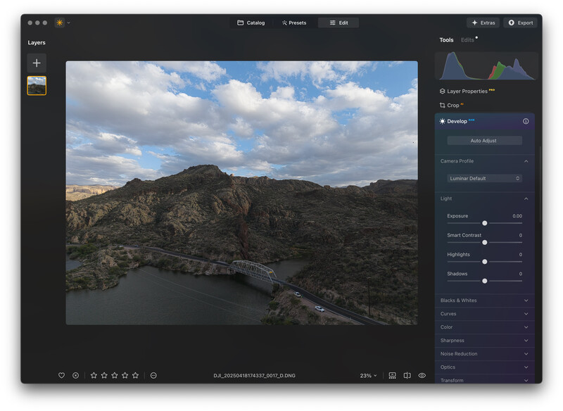 Screenshot of photo editing software showing a landscape image of a river winding through rocky terrain with mountains and cloudy sky.