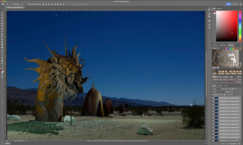Large wooden sculpture of a creature's head with spiky protrusions in a desert landscape with clear blue sky.