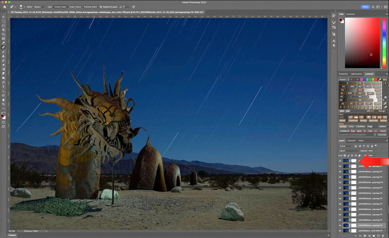 Wooden sculptural head with spiky protrusions in desert landscape under starry night sky.