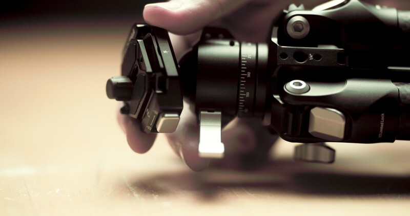 Close-up of hands holding a camera with telephoto lens and electronic viewfinder attachment.