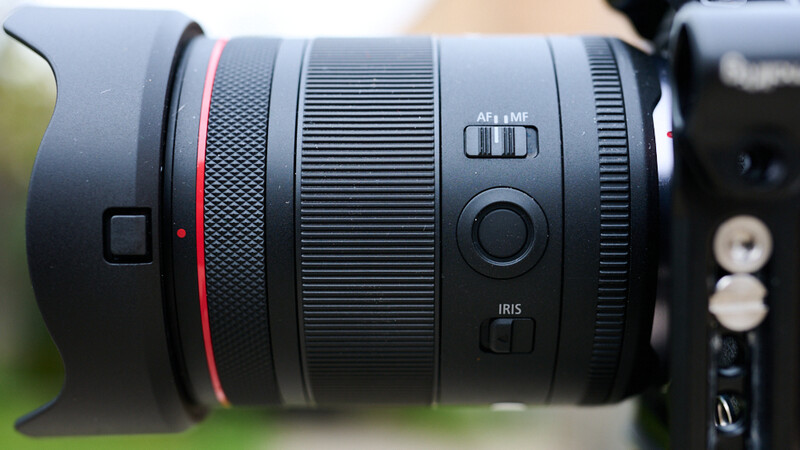 Close-up of a Canon RF-mount telephoto lens with red accent ring and AF+MF selector visible.