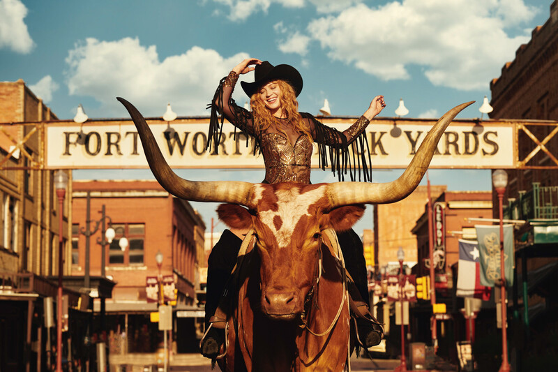 Cowgirl riding a Longhorn at the Fort Worth Stockyards