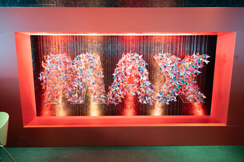 Four large sculptural forms with textured red and blue surfaces inside an illuminated red display frame.
