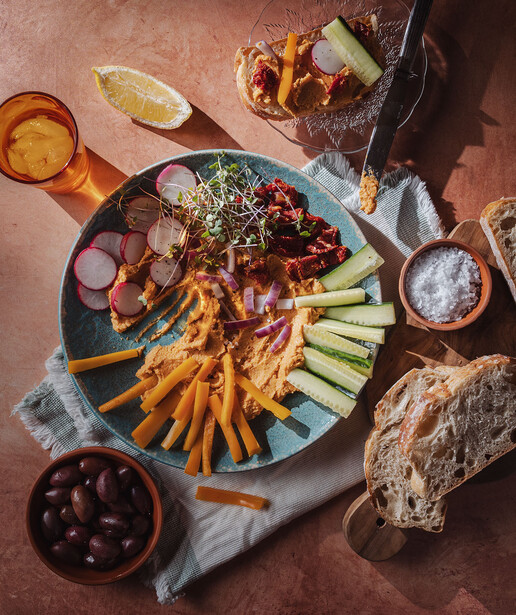Overhead flat lay of charcuterie and appetizers on a blue plate with fries, olives, bread, and condiments.