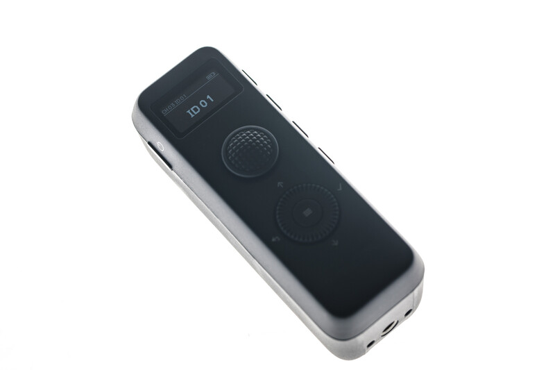 Handheld remote control with black face plate and silver sides, featuring a display screen and two circular control buttons.