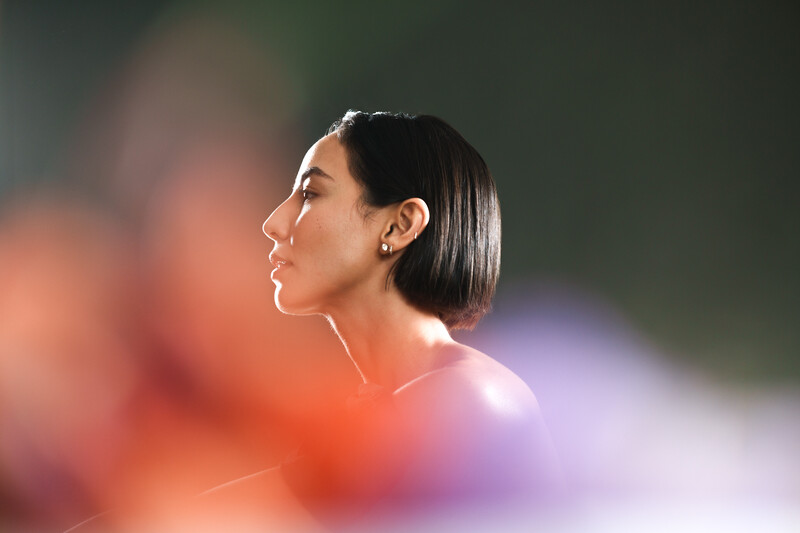 Woman's profile silhouetted against warm and cool-toned bokeh background.