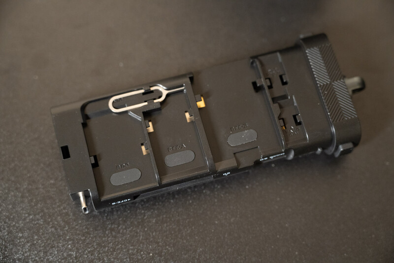 Battery power distribution hub with multiple battery slots and gold connectors on gray surface.