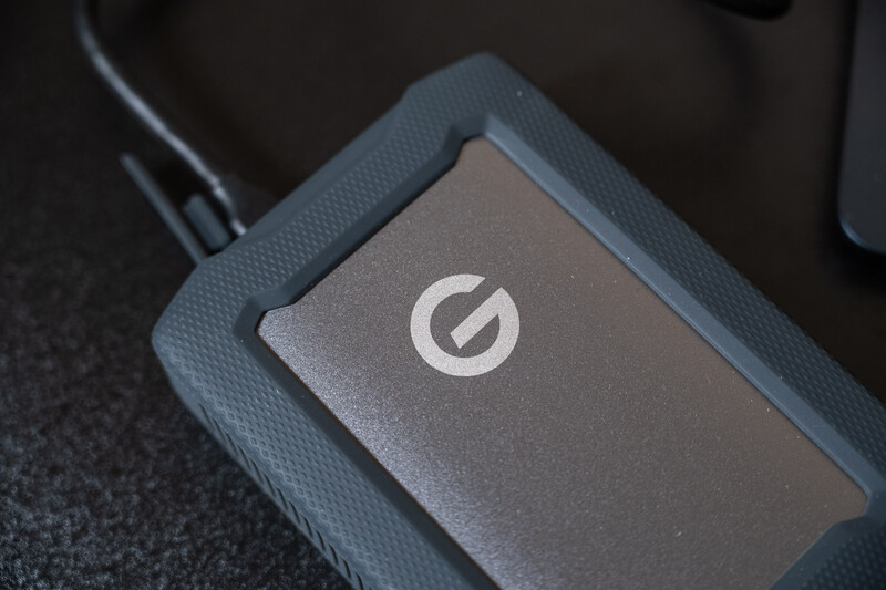 External hard drive with circular logo on textured fabric surface.