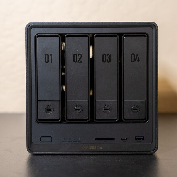 Black four-bay desktop storage enclosure with numbered compartments and front-panel controls.