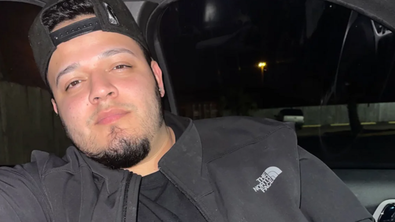 Man wearing black headband and jacket taking a selfie at night in a parking area.