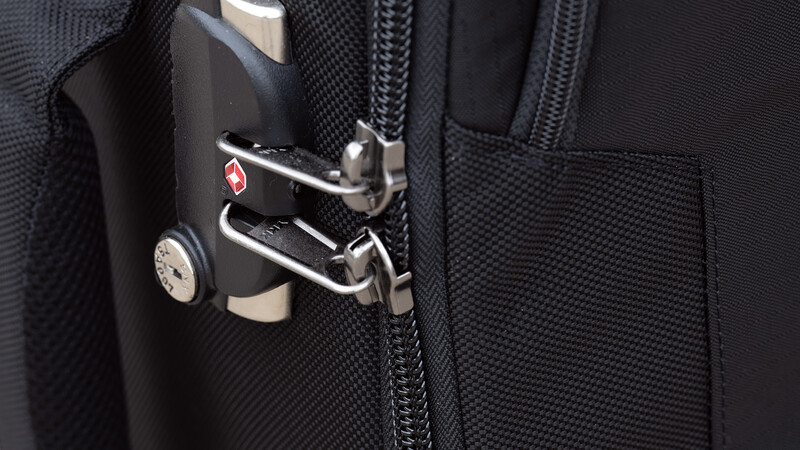 Close-up of a camera bag zipper pull with carabiner attachment and branded metal tag.