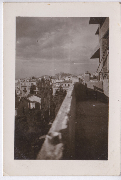 Urban rooftop view overlooking a dense cityscape with buildings receding into hazy distance.