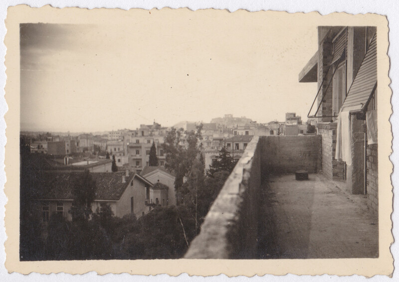 Cityscape view from a rooftop terrace showing densely packed buildings extending to the horizon.