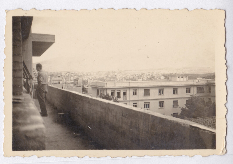 View from a rooftop terrace overlooking an expansive urban cityscape with residential buildings extending to the horizon.