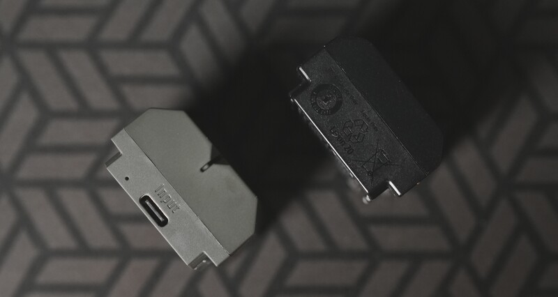 Two USB-C cables arranged on a geometric patterned surface, one white and one black, photographed from above in monochromatic lighting.