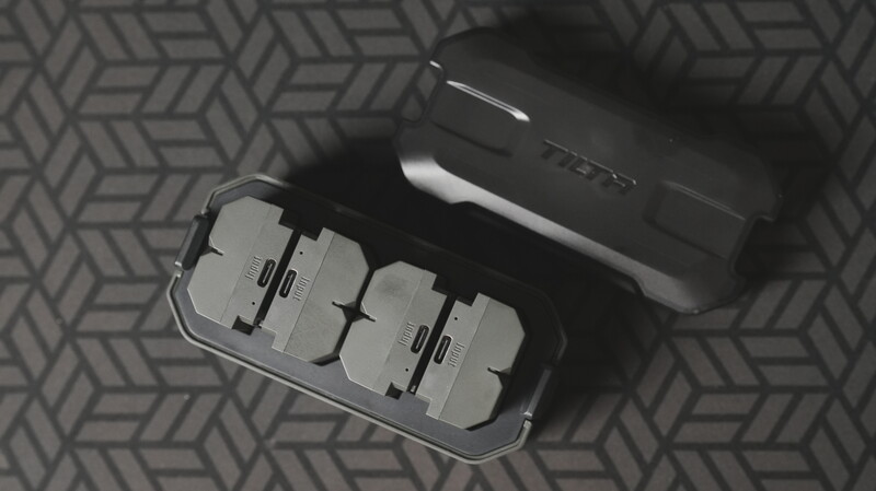 Flat lay of camera equipment and accessories on a patterned gray surface.