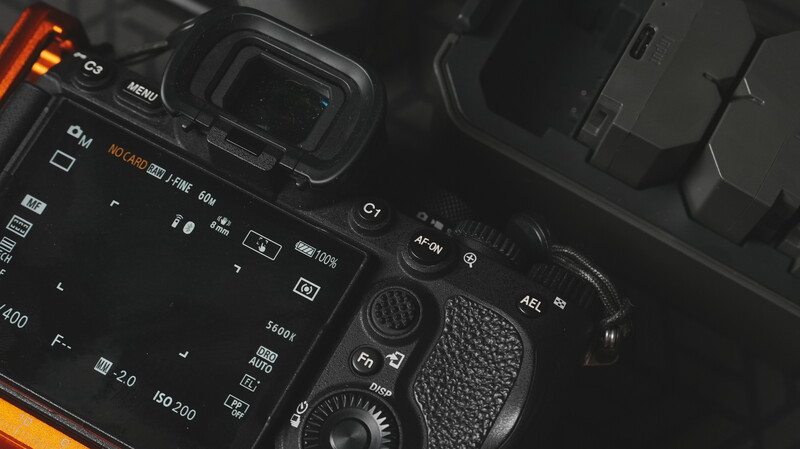 Top-down view of a professional camera body with control dials, buttons, and textured grip visible.