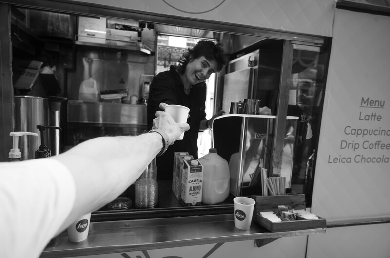 Arm reaching into a food truck to get a cup of coffee