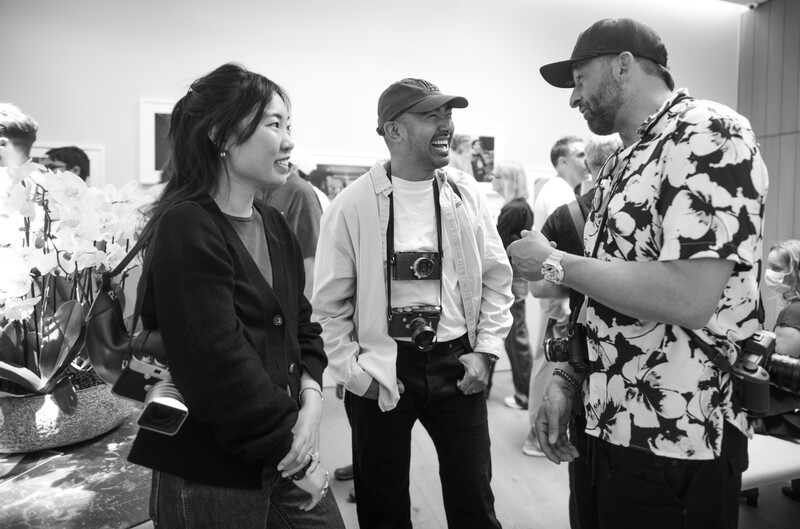 Three photographers talking in an art gallery