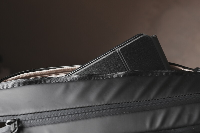 Close-up of a camera lens partially inserted into a gray padded camera bag with zipper detail.