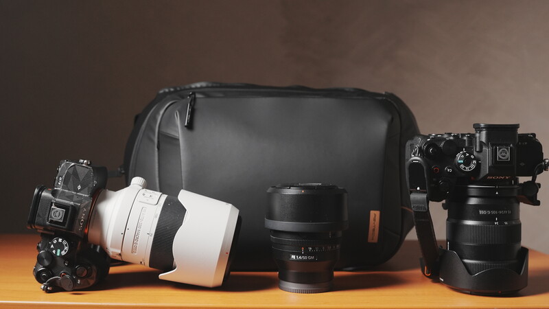 Camera gear and lenses arranged with a black camera bag against warm studio lighting.