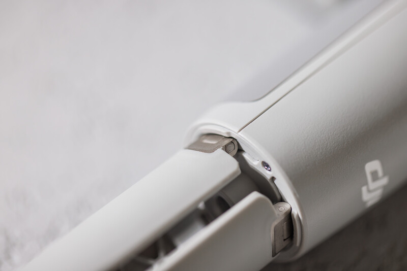 Close-up of a white camera lens focusing mechanism with visible mechanical components and metal hardware.