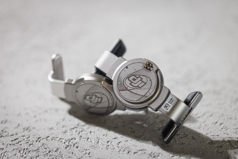Silver tattoo machine with dual coils and black grip displayed on concrete surface.