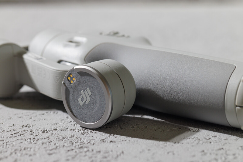 White wireless earbuds and charging case on textured concrete surface.