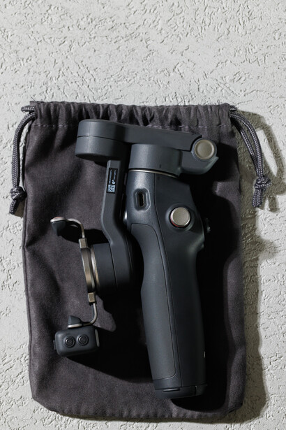 Gimbal stabilizer and accessories packed in a black drawstring canvas pouch.